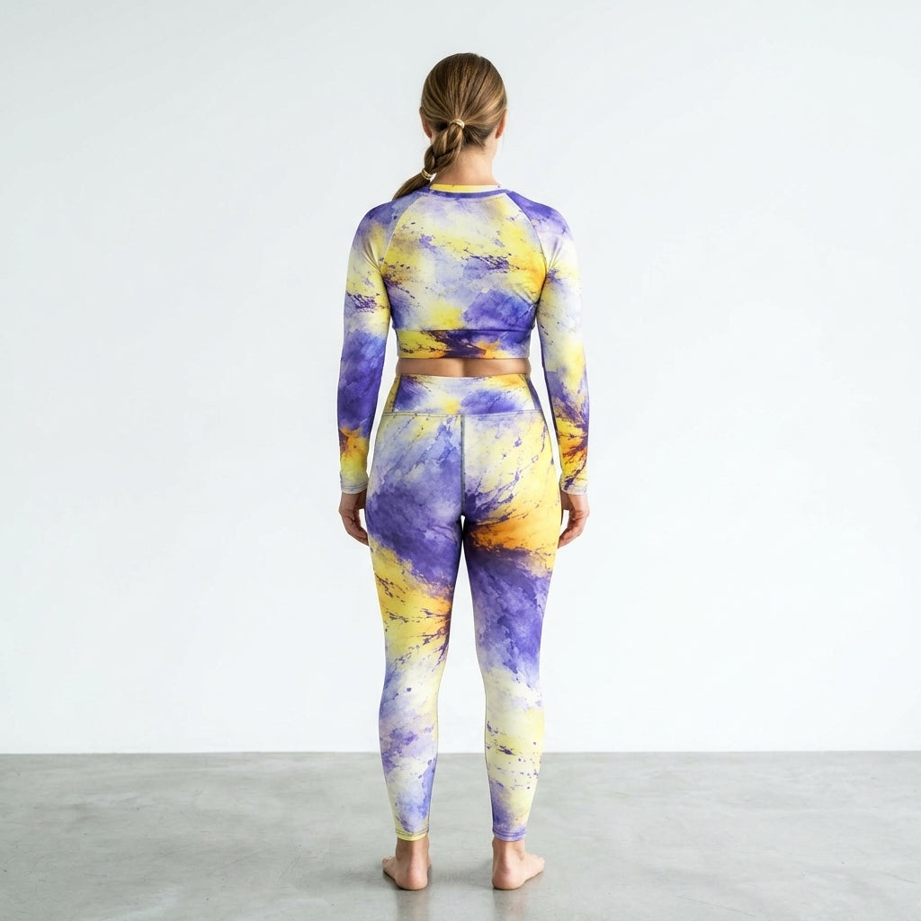 Model standing in a white studio wearing a Penny Purple Picotee activewear set.