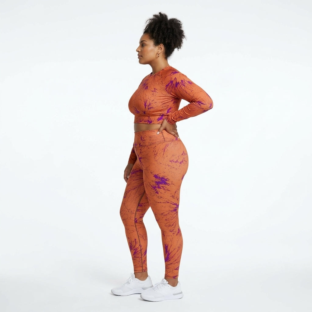 Model standing in a white studio wearing a matching Admire Orange Purple Wing athletic set.