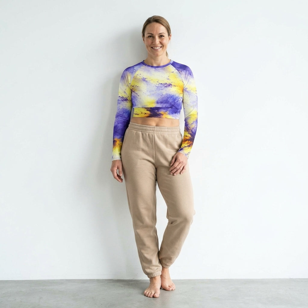 Model leaning against a studio wall wearing a Penny Purple Picotee long-sleeve crop top.